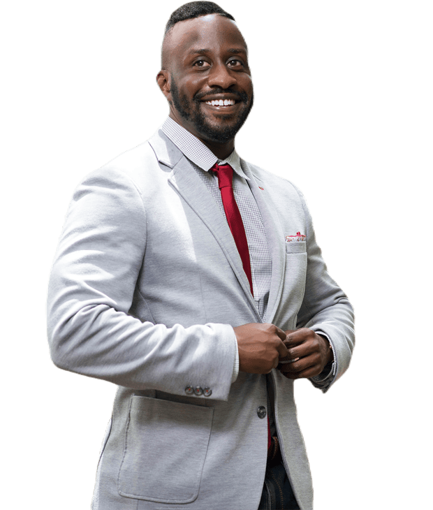Treaton McGlohoin, the CEO, smiles while adjusting his jacket, wearing a light gray blazer, red tie, and checkered shirt.