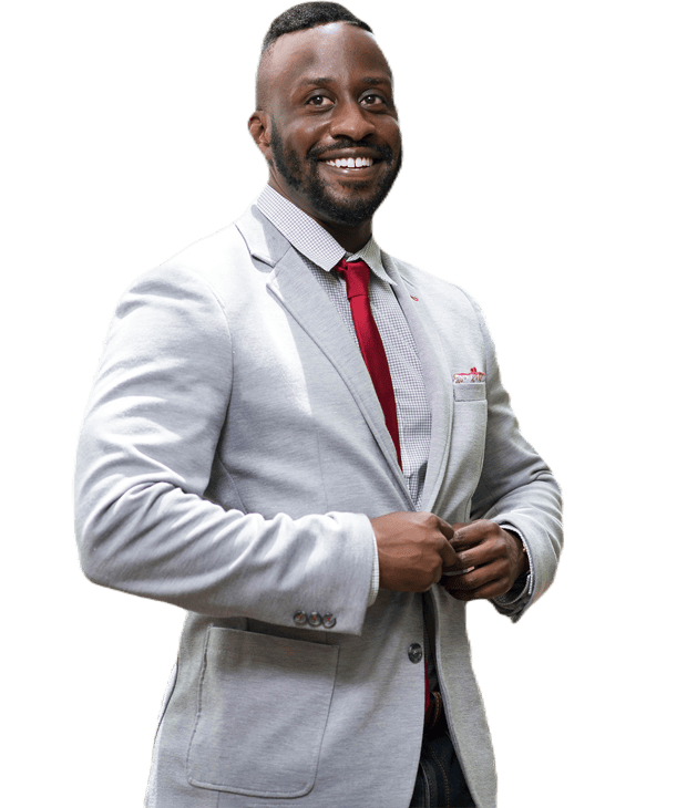 Treaton McGlohoin, the CEO, smiles while adjusting his jacket, wearing a light gray blazer, red tie, and checkered shirt.