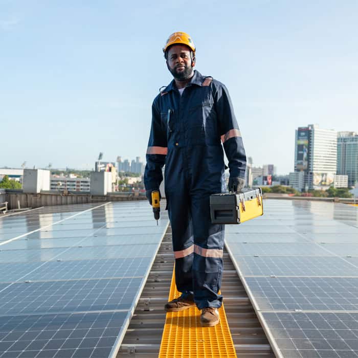 A technician wearing a hard hat and uniform stands on a rooftop with solar panels, holding a toolbox and a drill, seamlessly merging technical expertise with project finance management, city buildings standing tall in the background.